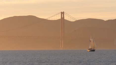 Sailing-Boat-Passing-Golden-Gate-Bridge-at-Sunset