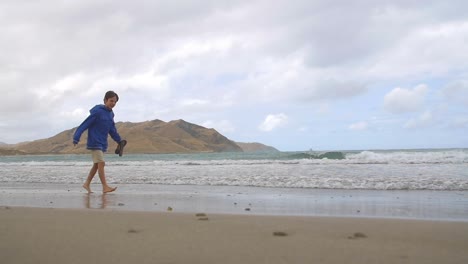 Young-Boy-Walking-Along-Windy-Beach