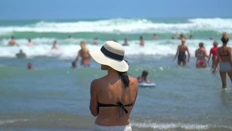 Woman-in-a-Hat-Standing-on-Beach