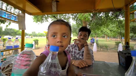 Indian-Toddler-Reaches-Through-Water-Bottles-