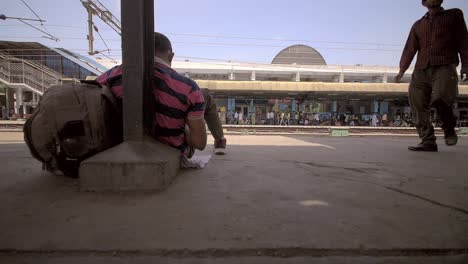 Man-Sitting-on-Train-Platform
