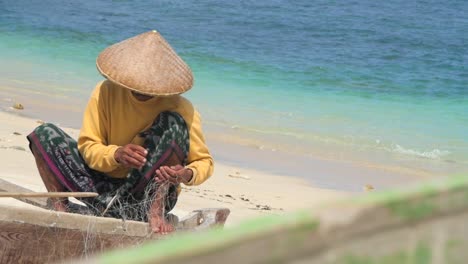 Pescador-desenredando-la-red-en-la-playa