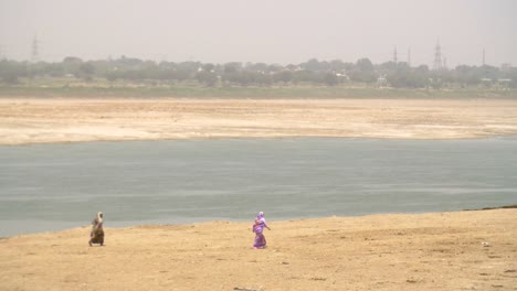 Two-Women-Walking-Along-Riverbank-in-Varanasi