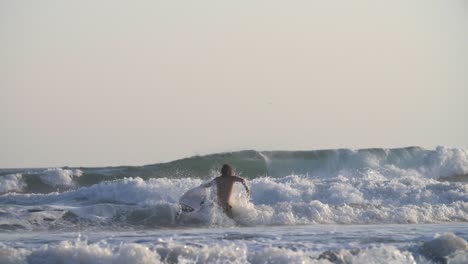 Surfer-Walking-Through-Large-Waves
