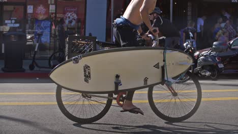 Man-Cycling-With-a-Surfboard