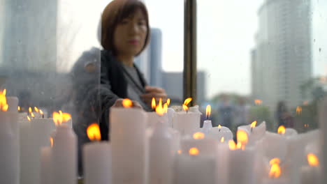 Woman-Lighting-a-Candle-at-a-Shrine