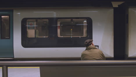 Man-sitting-on-bench-watching-train