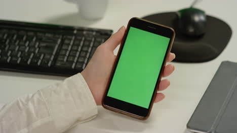 CU-Woman-at-Desk-Holds-Phone-with-Green-Screen