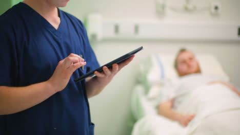 Enfermera-masculina-de-CU-tomando-notas-en-tableta