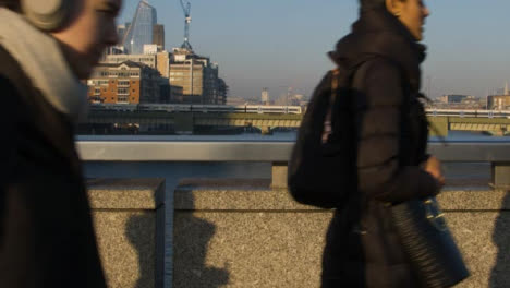 Pedestrians-Crossing-London-Bridge-With-Train-In-Background