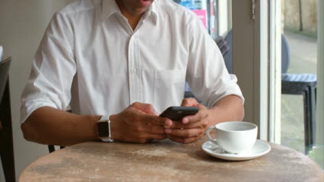Male-customer-sitting-in-cafe-using-smartphone,-mid-section