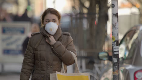 Woman-wearing-face-mask-and-coat-walking-on-street