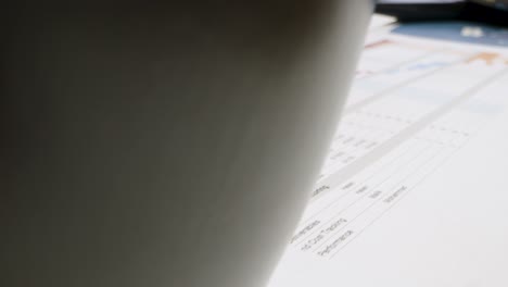 Close-Up-Project-Management-Printouts-on-Desk-With-Cup