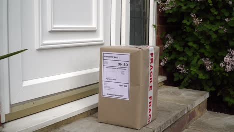 Male-Courier-Placing-Parcel-On-Doorstep