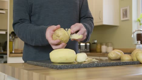 Man-Peeling-Potatoes-in-Kitchen