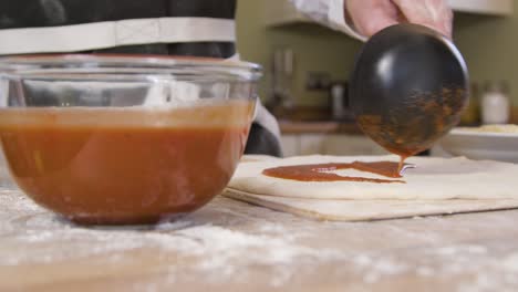 Male-Pouring-Tomato-Sauce-on-Pizza-Dough