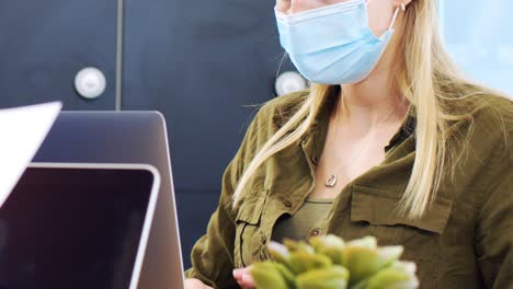 Young-Woman-in-Face-Mask-Typing-On-Laptop-In-Modern-Office