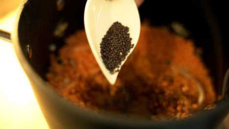 Extreme-Close-Up-of-Female-Hands-Adding-Mustard-Seeds-to-Lentils-