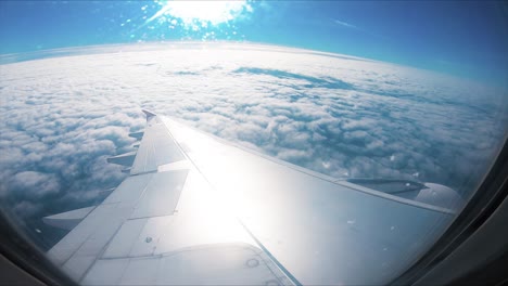 Airplane-flight.-Wing-of-an-airplane-flying-above-the-clouds-with-sunset-sky.-View-from-the-window-of-the-plane.-Airplane,-Aircraft.-Traveling-by-air.-Optical-flares.