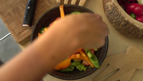 Close-Up-of-Female-Hands-Placing-Green-Pepper-In-Salad-Bowl