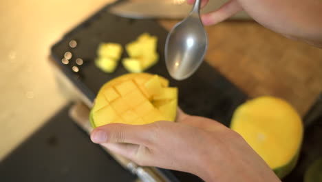 Close-Up-of-Female-Hands-Scooping-Chunks-of-Mango