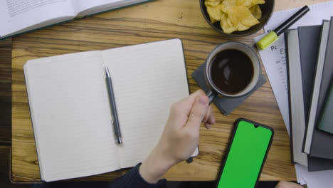 Mann-Stellt-Kaffee-Ab-Und-Scrollt-Auf-Smartphone-Mit-Grünem-Bildschirm