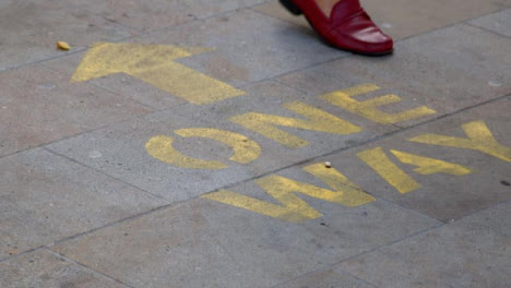 Close-Up-Shot-of-Feet-Walking-Over-One-Way-Pavement-Marking