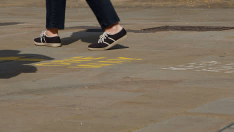 Close-Up-Shot-of-Feet-Walking-Over-One-Way-Pavement-Marking-In-Oxford