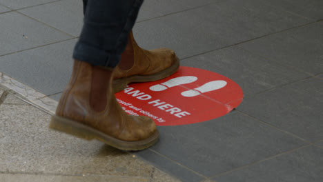 Close-Up-Shot-of-Feet-Standing-On-Stand-Here-Floor-Sign