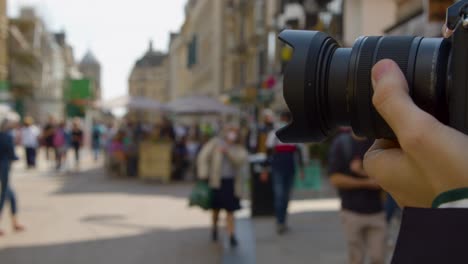 Close-Up-Shot-of-Man-Using-Focus-Ring-On-Camera-In-Busy-Street