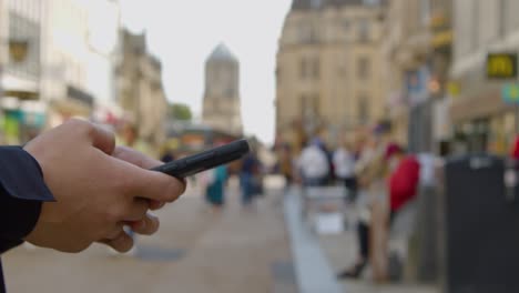 Panning-Shot-of-Man-Texting-On-Mobile-Phone-In-Busy-Street-In-Oxford