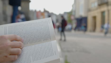 Close-Up-Shot-of-Someone-Reading-a-Book-On-Clarendon-Building-Steps-In-Oxford