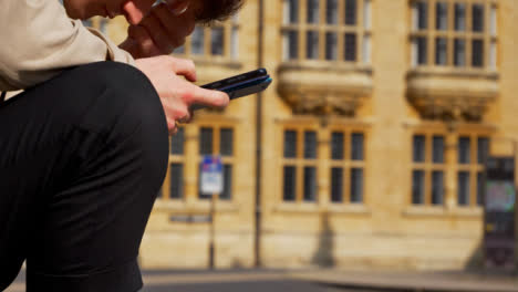 Close-Up-Shot-of-Man-Looking-at-Phone-On-Old-Street-In-Oxford-01