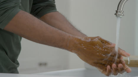Man-Cleaning-His-Hands-with-Soapy-Water-Under-a-Running-Tap-