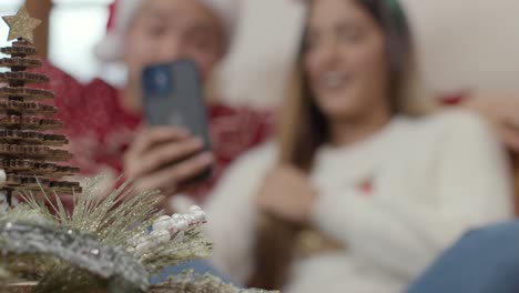 Extreme-Close-Up-of-Christmas-Decorations-As-Couple-In-Background-Interact-with-Phone