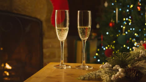 Close-Up-of-Two-Glasses-of-Champagne-On-Table-In-Front-of-Fireplace