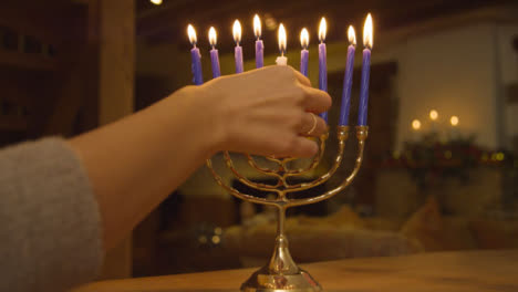Close-Up-Shot-of-Female-Hand-Lighting-Candles-On-Menorah-During-Hanukkah-Celebration