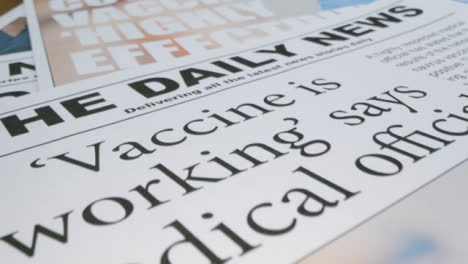 Sliding-Extreme-Close-Up-of-Pile-of-Newspaper-Front-Pages-with-Covid-19-Vaccine-Headlines