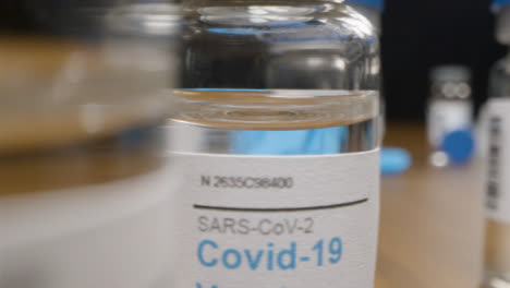 Sliding-Close-Up-Shot-Past-Syringes-and-Several-Vials-of-Coronavirus-Vaccine-