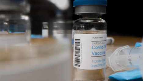 Sliding-Close-Up-Shot-Past-Syringes-and-Several-Vials-of-Covid-19-Vaccine-