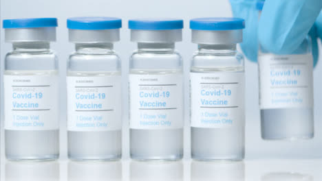 Sliding-Close-Up-Shot-of-Five-Vials-of-Covid-Vaccine-as-Hand-Takes-One-Away