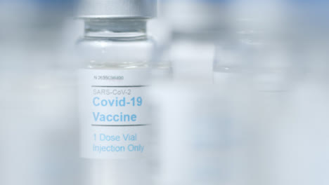 Extreme-Close-Up-Pull-Focus-Shot-Through-Multiple-Vials-of-Covid-Vaccine