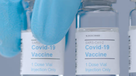 Sliding-Extreme-Close-Up-Shot-Along-Line-of-Covid-Vaccine-Vials-As-Hand-Takes-One-Away