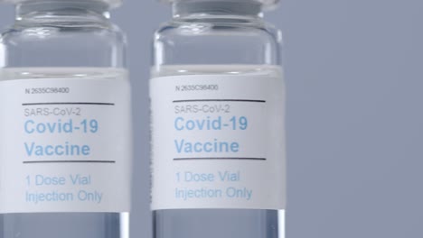 Sliding-Extreme-Close-Up-Shot-Along-Line-of-Covid-Vaccine-Vials-As-Hand-Takes-One-Away