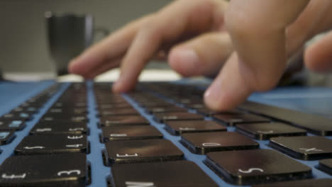 Sliding-Extreme-Close-Up-Shot-of-Pair-of-Male-Hands-Typing-On-Laptop-Keyboard