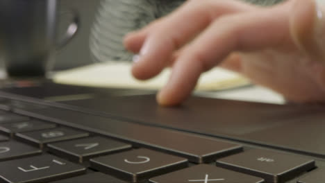 Sliding-Extreme-Close-Up-Shot-of-Male-Hands-Using-a-Laptop-Keyboard-and-Trackpad