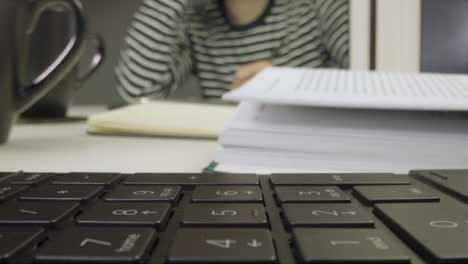 Sliding-Extreme-Close-Up-Shot-of-a-Laptop-Keyboard-and-Two-People-Reading-Books