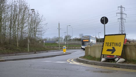 Wide-Shot-of-Bus-Passing-COVID-19-Testing-Site-Road-Sign