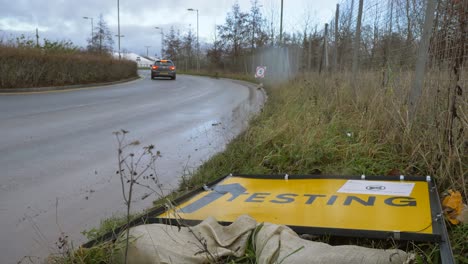 Wide-Shot-of-Car-Driving-Away-From-Fallen-Over-COVID-19-Testing-Site-Road-Sign
