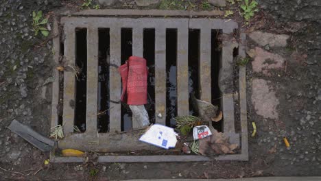 Handheld-High-Angle-Shot-Looking-Down-at-a-Discarded-Face-Mask-In-Drain-